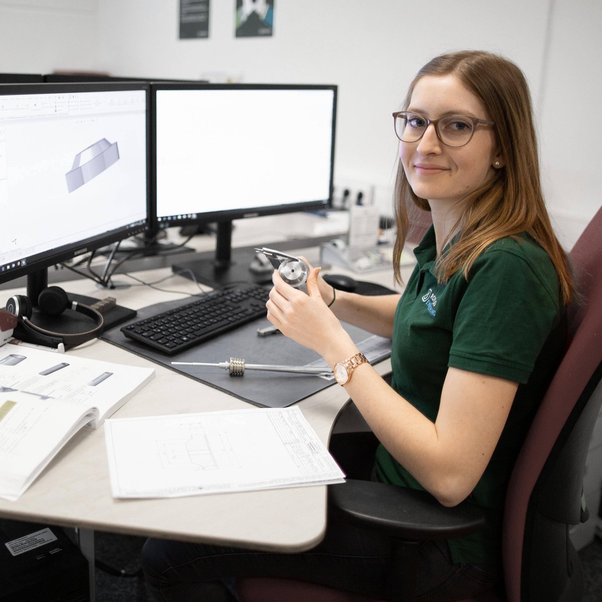 Young trainee at desk with open 3D model and mechanical component in hand
