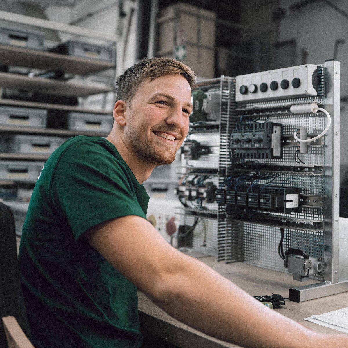 Junger Mann beim Arbeiten an zwei kleinen elektronischen Kabeln am Schreibtisch