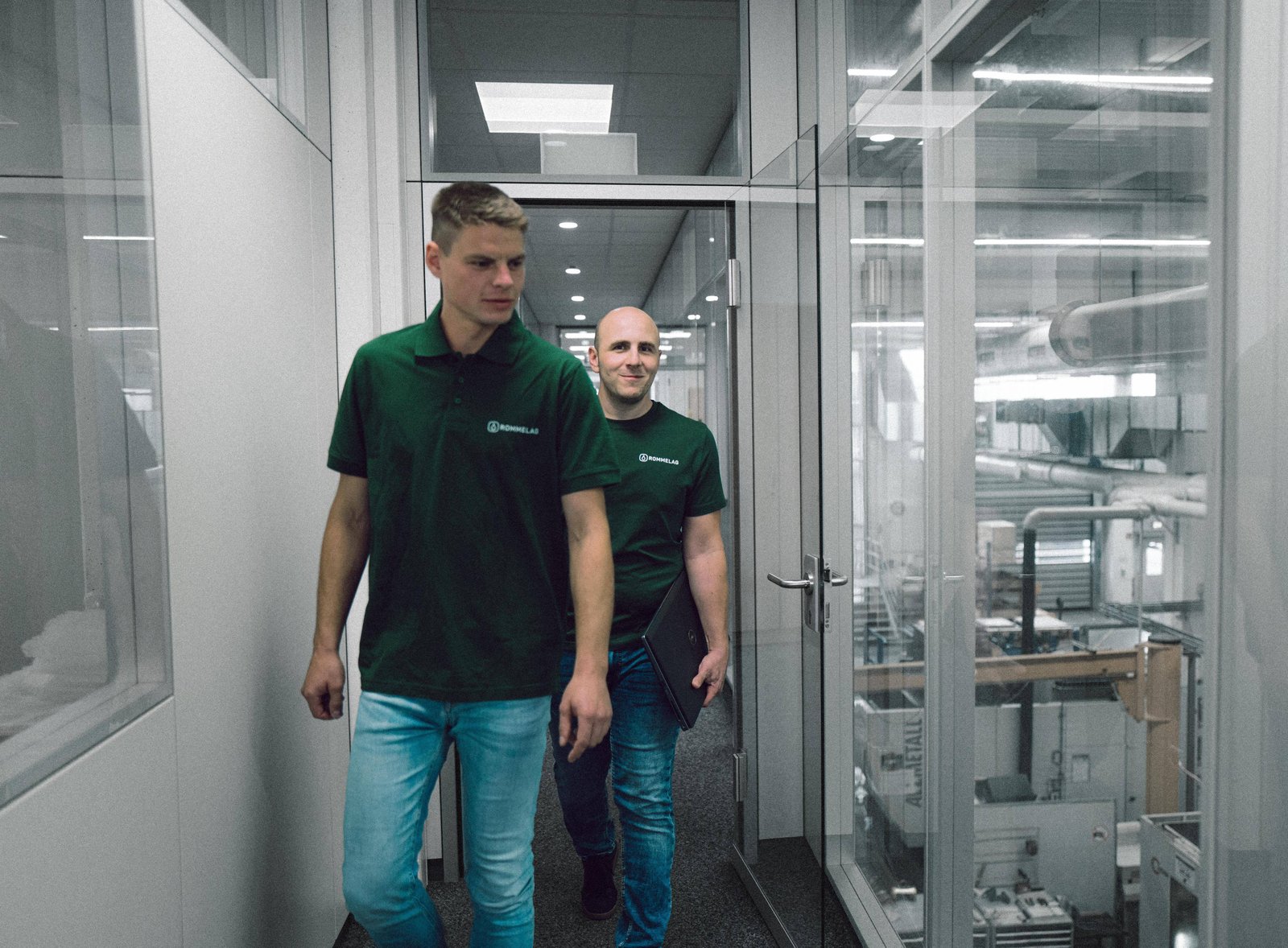 Zwei Männer laufen durch einen Gang eines Maschinenlabors