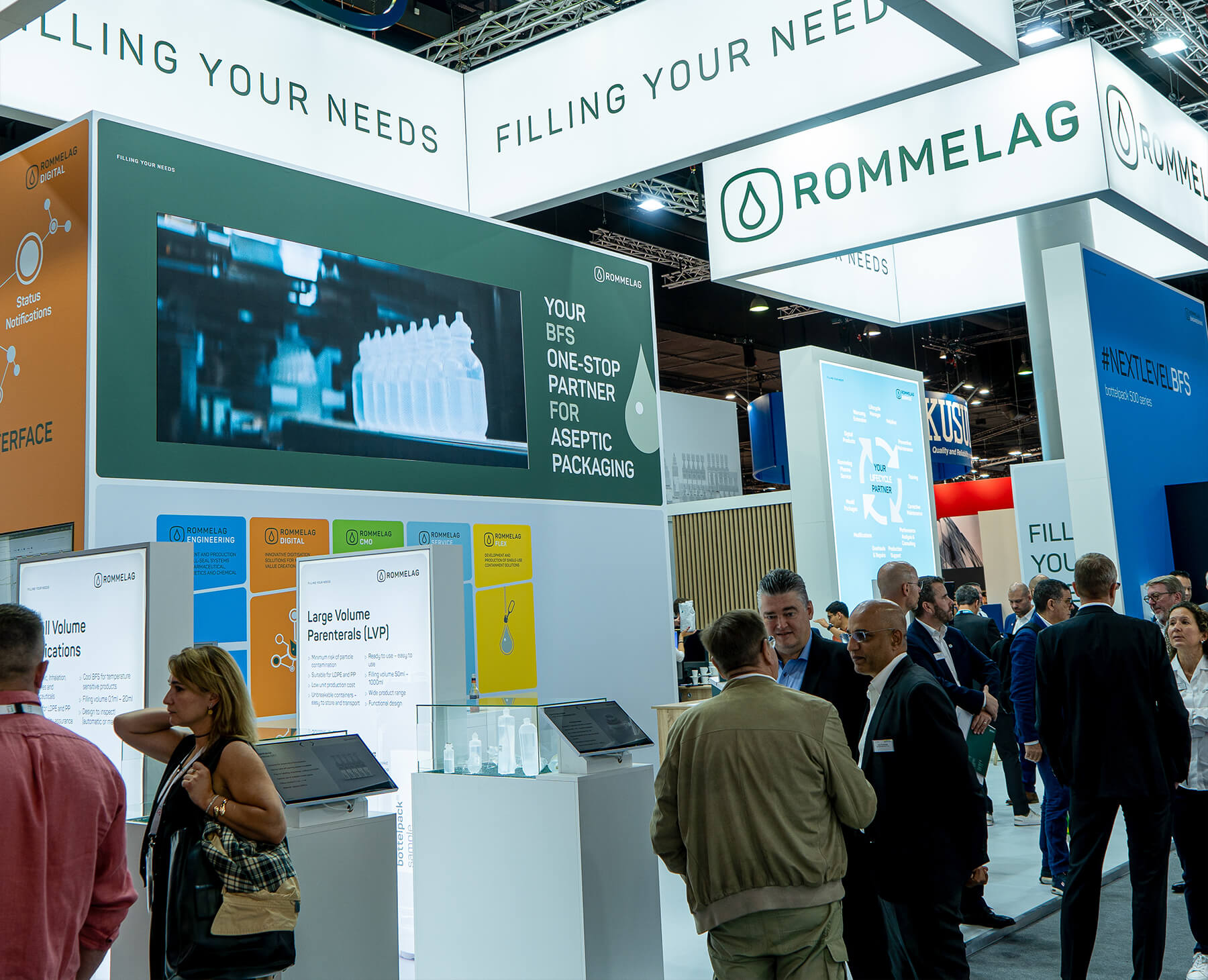 Fotografie die den Messestand von Rommelag zeigt und Interessenten am Stand die sich im Dialog mit Rommelag Mitarbeitern befinden.